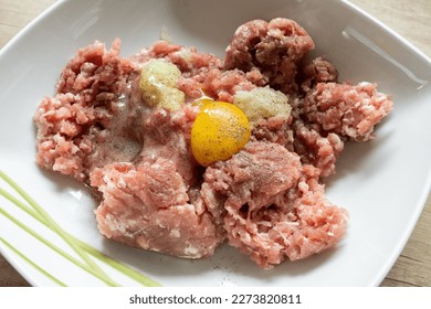 Minced meat, egg, onion and spices in a bowl. Preparing minced cutlets in Poland, traditional Polish kotlety mielone.