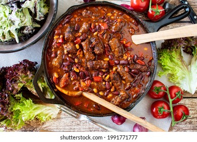 Minced Meat Stew With Beans In A Spicy Tomato Red Pepper Sauce Served In A Rustic Cast Iron Pan With A Fresh Salad