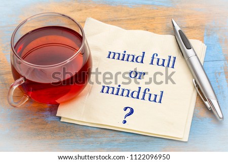 Mind full or mindful   Inspiraitonal handwriting on a napkin with a cup of tea.