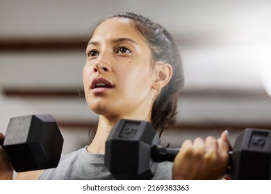 Mind Over Matter. Low Angle Shot Of A Sporty Young Woman Exercising With Dumbbells In A Gym.