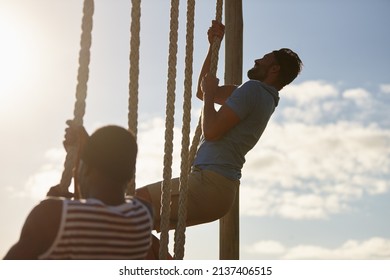 Mind over matter. Shot of two young men climbing up ropes at a military bootcamp. - Powered by Shutterstock