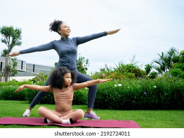 Mindful African Mom With Cute Funny Kid Daughter Doing Yoga Exercise At Park.calm Black Mother And Mixed Race Little Girl Doing Yoga In City Park Nature Together, Mum Teaching Child To Meditate.