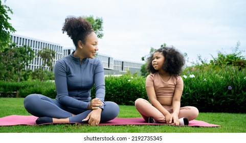 Mindful African Mom With Cute Kid Daughter Doing Yoga Exercise Outdoor.calm Black Mother And Talking Little Girl Sitting In Lotus Pose On Couch Together, Mum Teaching Child To Meditate.