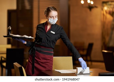 Mindful cafe worker using mask while serving the table