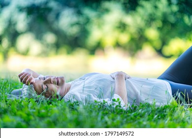 Mindful Mature Woman Meditating By The Water, Lying Down, Feeling Connected To The Earth And Nature