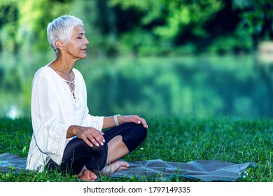 Mindful senior woman meditating by the body of water - Powered by Shutterstock