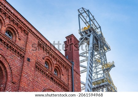 Mine shaft tower 'Krystyn' in former coal mine 'Michal' in Siemianowice, Silesia, Poland against blue sky. Historical, brick building of the engine room in the foreground.