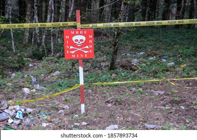A minefield warning in the forest near the frontlines. Red minefield sign in Bosnia and Herzegovina. Warning sign: Stop, dangerous, landmine.
