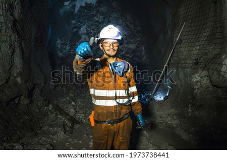 Miner in the mine. Well-uniformed miner inside mine raising thumb, conceptual photo