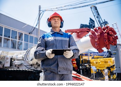 Miner Operator In Helmet With Tablet Computer Control Drilling Machine In Coal Mine. Concept Smart Industrial Mining.