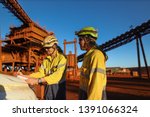 Miner supervisor engineer wearing safety fall protection helmet read and sign permit to work before hand over working at height paper book to contractor construction mine site, Sydney, Australia  