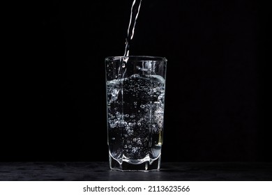 Mineral water is poured into a glass on a black background. Useful drinking mineral water. - Shutterstock ID 2113623566