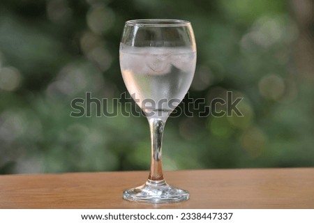 Mineral water in a wineglass with ice, with fogged glass due to high outside temperature