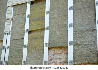 The Mineral Wool Outside Insulation Of An Old Brick House With Exterior Vinyl Wall Siding Panels Installation On Starter Strips During An Old House Renovation. 