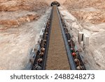 Minerals being transported on a long conveyor belt at a copper mine.