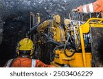 Miners operate heavy machinery in a dark, underground mine tunnel