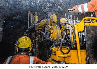 Miners operate heavy machinery in a dark, underground mine tunnel - Powered by Shutterstock