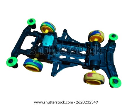 A mini 4WD car frame without a body with colorful wheels and a motor in the middle. Seen from above.