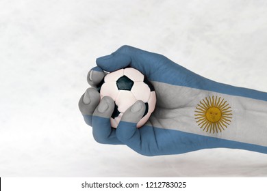 Mini ball of football in Argentina flag painted hand on white background. Concept of sport or the game in handle or minor matter.