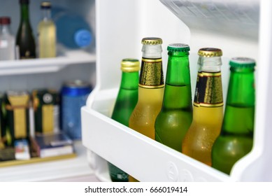 Mini Bar Full Of Bottles Of Juice And Water In Hotel Room. The Open Door Of Mini Fridge. Cold Beer In Home Bar. Drink And Food Inside Small Refrigerator.