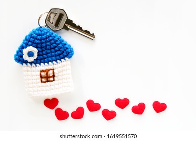 Mini Blue Roof Crocheted House And Key With Red Hearts As Stepping Stones On White Background, From Top View. Concept For Family, House Insurance, Financial Home Loan Or Money Saving For House Buying