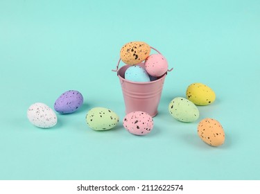 Mini bucket with colored Easter eggs on blue background. Easter minimal concept. Creative Happy Easter, spring layout.