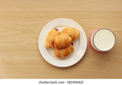 Mini bun bread in dish and milk on wooden table