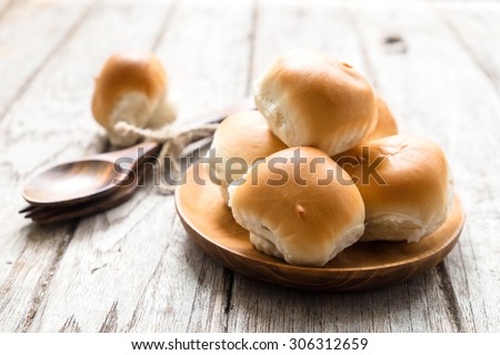 Mini bun bread in wooden plate on wooden floor
