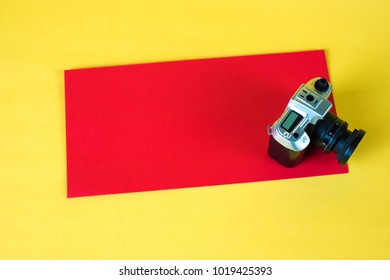 Mini camera toy and red envelop on yellow background with copy space for add text.