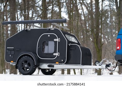 Mini Camper Towed By Car In The Winter Snow Woods. Family Journey Time Together Away In The Forest Wild Life. Pick Up Truck With RV Travel Trailer Driving Though National Park. 