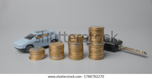 Mini car model and key with stack\
of golden coins,saving for car,loan and financial\
concept