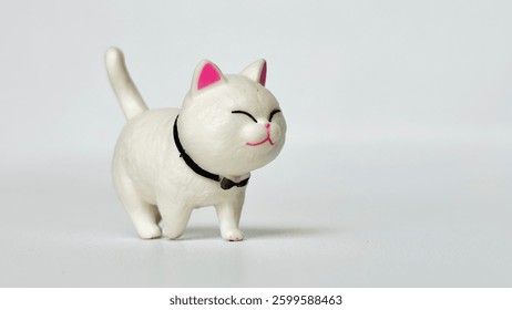 Mini cat doll made of plastic. With a happy smiling face. Walking on the white floor. White cat. Free space for text.
