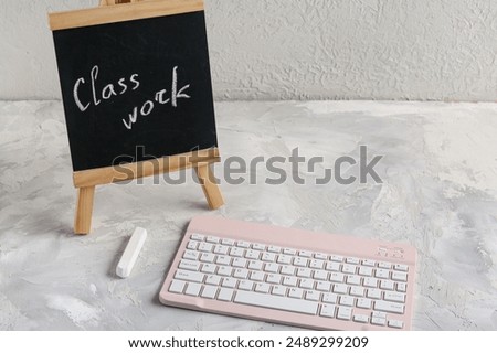 Mini chalkboard with text CLASSWORK and modern keyboard on grunge background