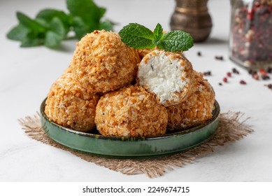 Mini cream cheese balls with mint covered in chopped nuts served on a plate.