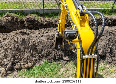 Mini digger digging a hole in the garden along the fence to the drainage pipes. - Shutterstock ID 2300209111