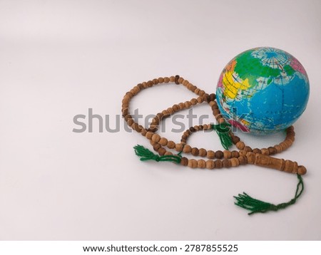 A mini Earth globe model sits alongside coiled wooden prayer beads featuring deep green decorative tassels.