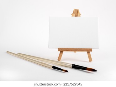 Mini Easel With White Blank Empty Horizontal Canvas, Paint Brushes. Art Concept. High Quality Photo