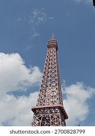 Mini Eiffel Tower Against Vibrant Blue Sky: A Symbol of Parisian Charm in Unexpected Places