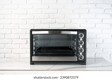 Mini horno eléctrico contra pared de ladrillo blanco en la cocina