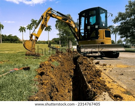 mini excavator digger excavates a trench hole for water pipe line