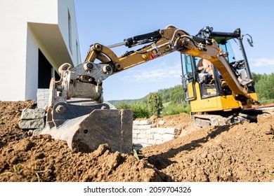 Mini excavator digging preparing ground under home garden - Powered by Shutterstock