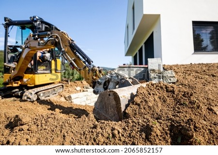 Mini excavator digging preparing ground under home garden