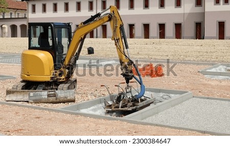 Mini excavator with special attachment during a parking lot construction.