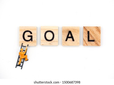  Mini Figure Of Man Climbing Ladder To The Word Goal , Business Goal Concept.