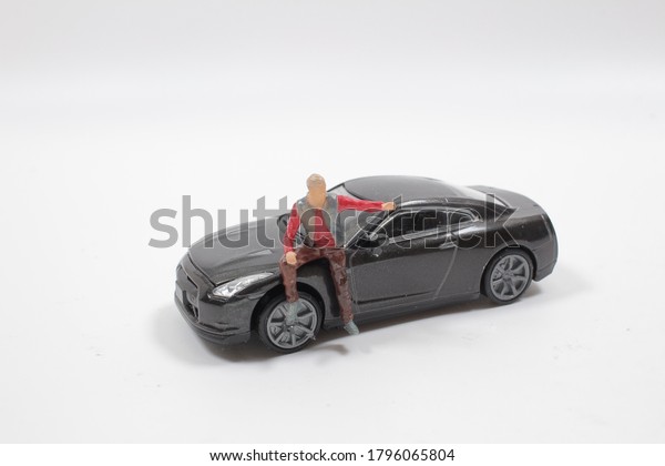 the mini figure sit in\
front of a car