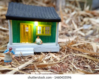 Mini Figure Toy Indonesian Woman Cleaning The Terrace And Old Man Using Sarung, Kopiah And White Shirt, Sit At His House, Beyond Bamboo Forest With Copy Or Negative Space For Text Placement Area