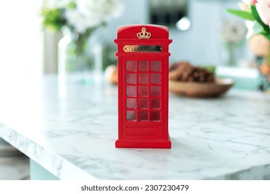 Mini figurine of London Telephone Booth for sale as souvenir. Telephone booth present. Red british phone booth statuette decoration room. 
				Figurine of a red telephone booth on shelf. 