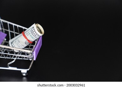 Mini Food Basket With 100 Dollars On A Black Background. Investing And Storing Money. The Concept Of Frugality And Financial Literacy.