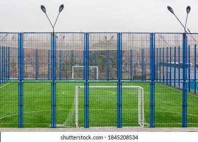 Mini football court. View on mini-football court with artificial grass through blue fence on a foggy autumn day. Sport concept: football field and soccer goal with grass flooring. Nobody, foggy day. - Powered by Shutterstock