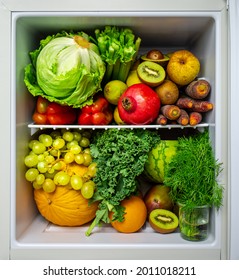 Mini fridge packed with healthy fruits and veggies. Eating healthy and plant-based in a small space. Lettuce, kiwi, dill, honeydew, grapes, orange, pomegranate.